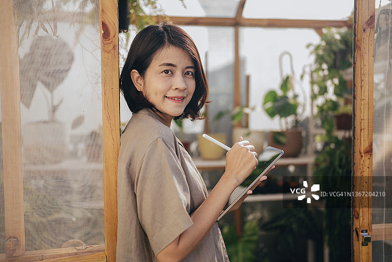 花艺师在园艺中心检查植物并使用平板电脑图片素材