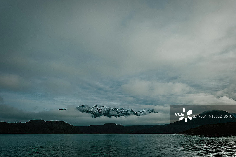 新西兰湖面上云层之上的雪山山峰图片素材