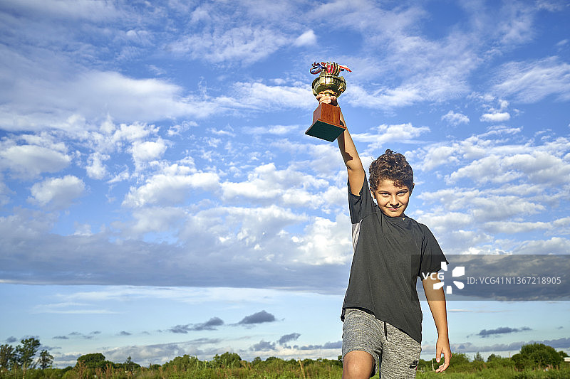 快乐的男孩手持奖杯图片素材