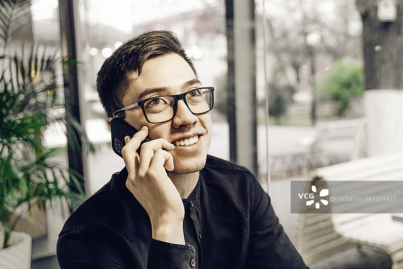 年轻英俊的亚洲男子正在打电话并微笑图片素材