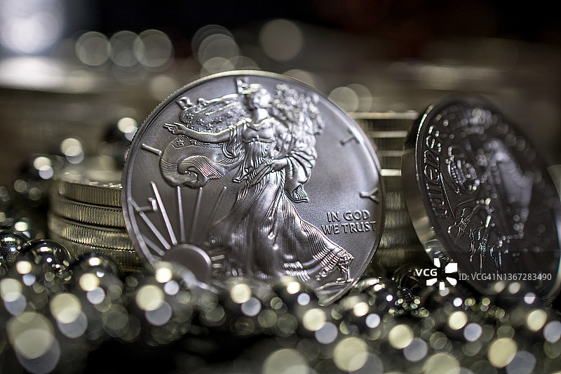 美国自由女神银币与银球轴承堆的特写，深色背景图片素材