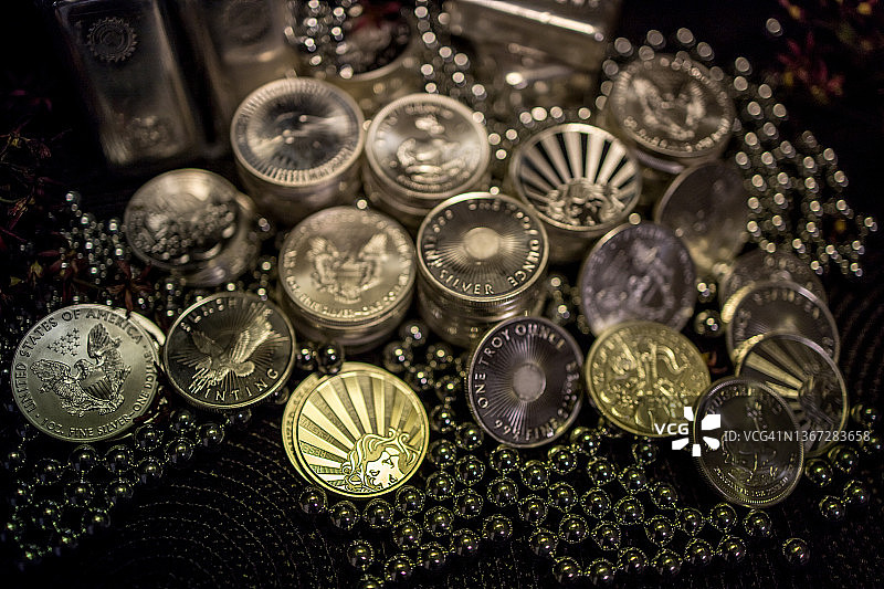 金银币和银球轴承，深色失焦背景图片素材