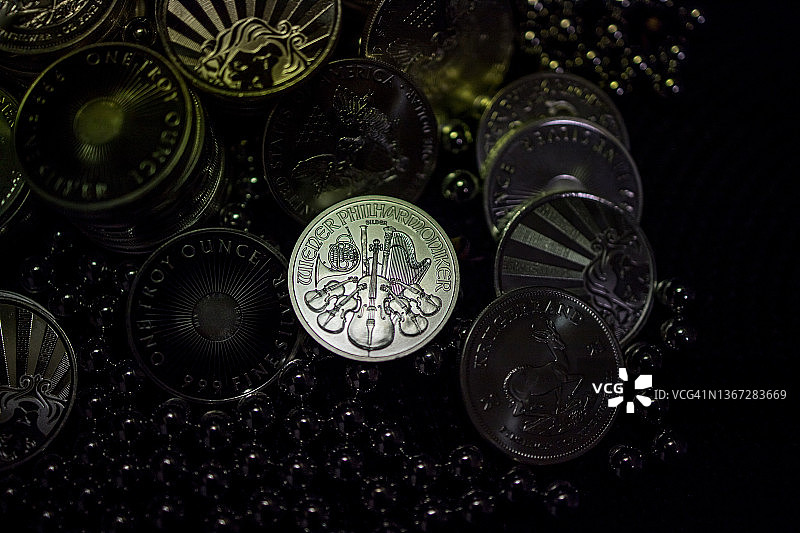 维也纳爱乐银币在众多硬币堆中，深色背景图片素材