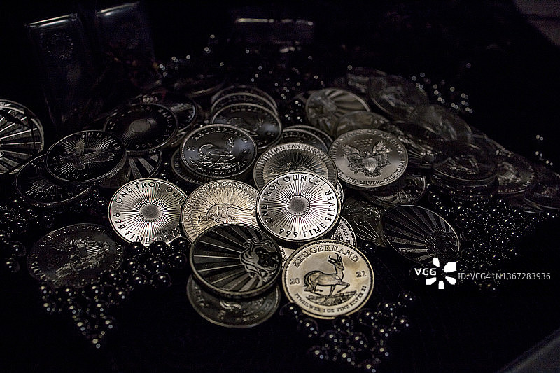 深色背景下银色滚珠中的一堆银币图片素材