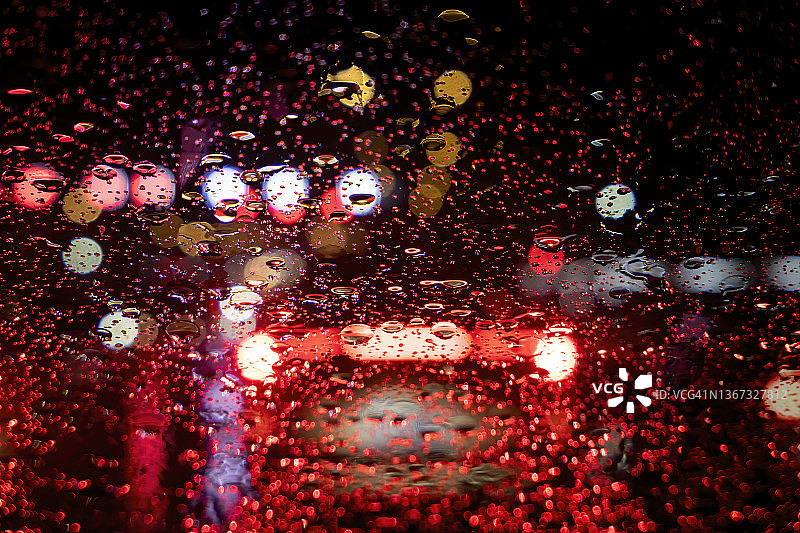 雨夜，被水浸湿的车窗玻璃反映出五彩缤纷的圆形车头灯光点图片素材
