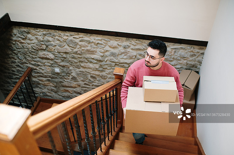 年轻男人搬着纸箱上楼梯图片素材
