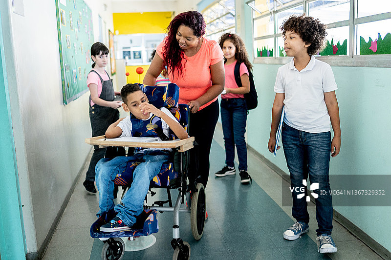 学校走廊里行走的老师和学生们，包括一位有特殊需求的人图片素材