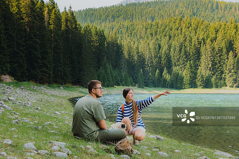 男女游客带狗在黑山风景秀丽的山间湖泊欣赏日出图片素材