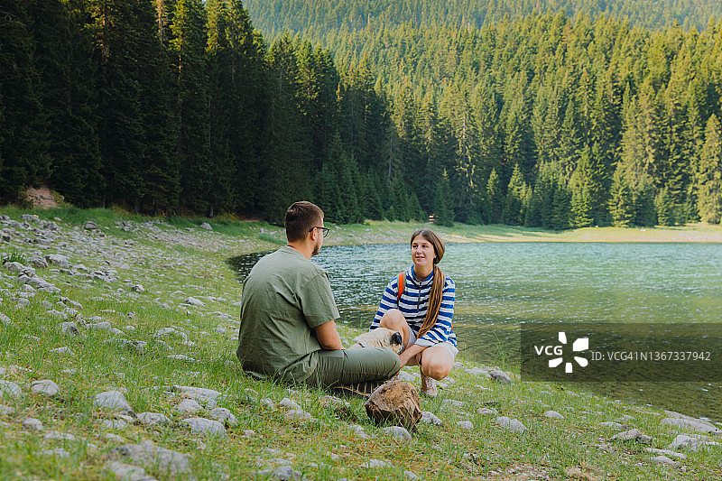 男女游客带狗在黑山风景秀丽的山间湖泊欣赏日出图片素材