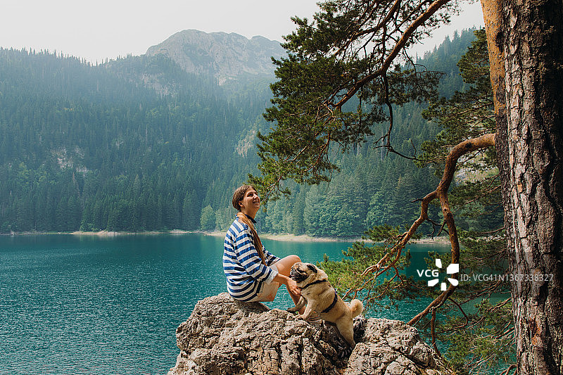 女旅行者在黑山风景如画的山间湖泊与她的狗一起漫步，沉思夏日图片素材