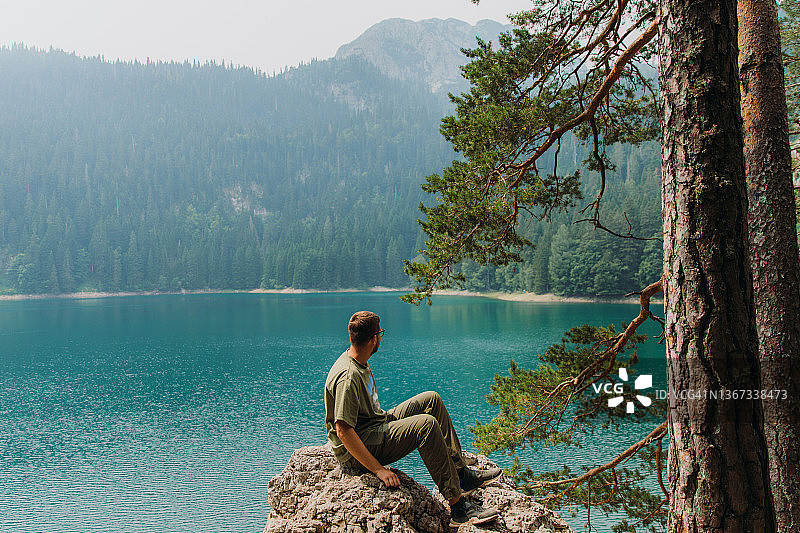 男人带着狗在黑山风景秀丽的湖边漫步，欣赏夏日风光图片素材
