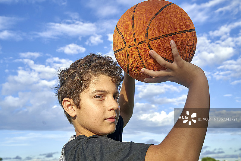 有着卷发的可爱男孩抱着篮球图片素材