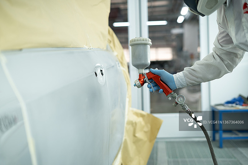 汽车修理店：油漆工使用喷涂压缩机喷漆图片素材