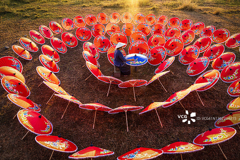 中年女艺术家在色彩缤纷的雨伞场景中绘画图片素材