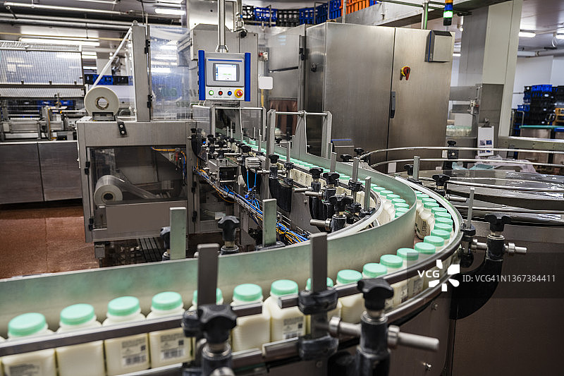 传送带在工厂中输送弯曲的牛奶瓶图片素材