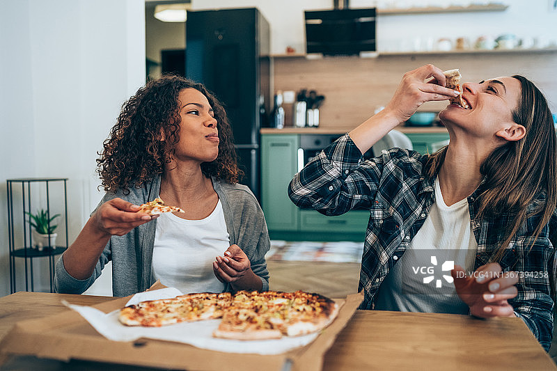 两位年轻女人在家一起吃披萨图片素材