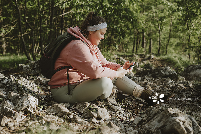 在森林里用手机聊天的超重妇女图片素材