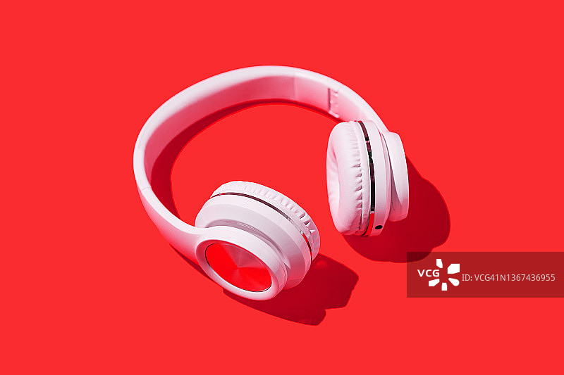 红色背景上的白色无线耳机：音乐、耳机和放松概念图片素材