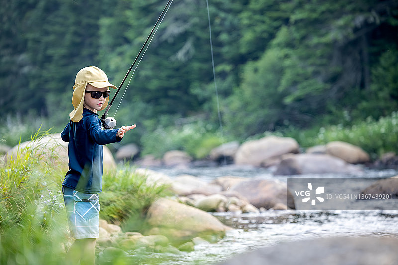 在魁北克河里钓鱼的可爱红发男孩图片素材