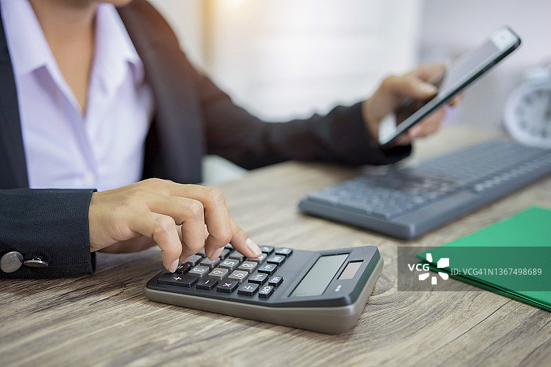 商务概念：办公室里使用计算器和笔记本电脑的商人图片素材