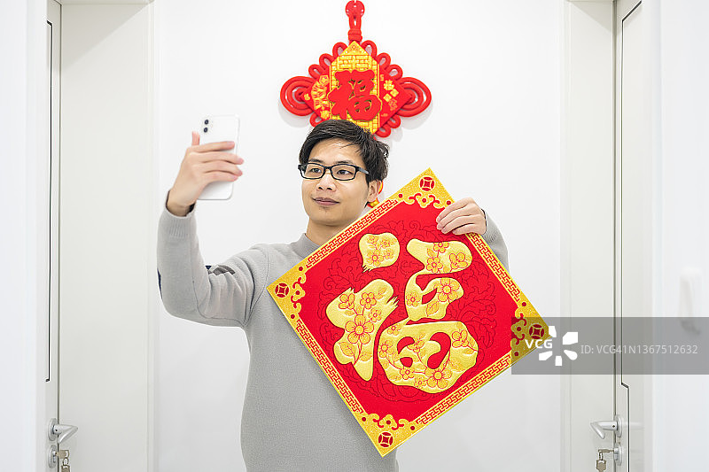 亚洲男子视频通话展示“福”字春联图片素材