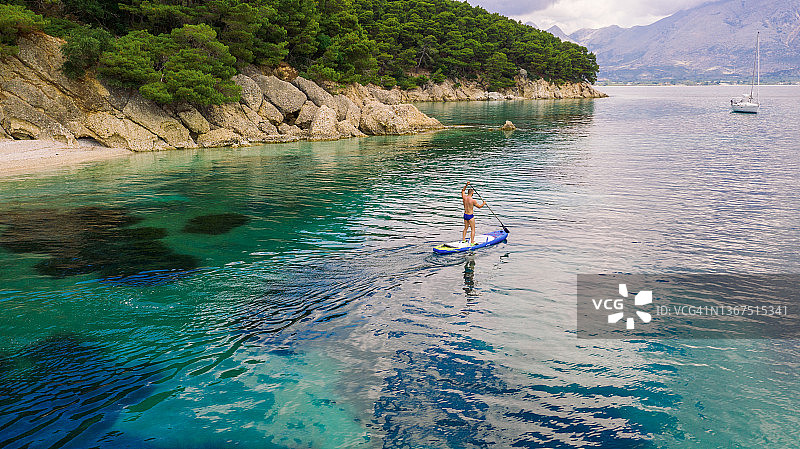 男人在平静美丽的海面上划桨板图片素材