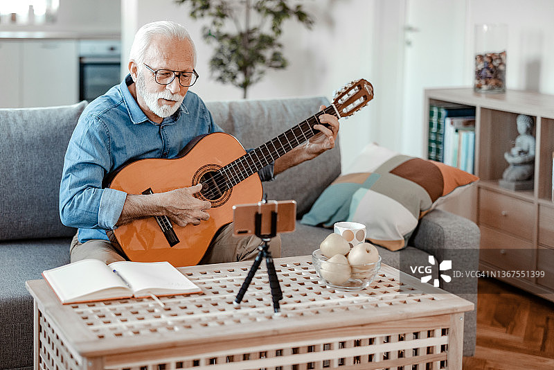 留着胡须的老年男人制作关于吉他的视频博客图片素材