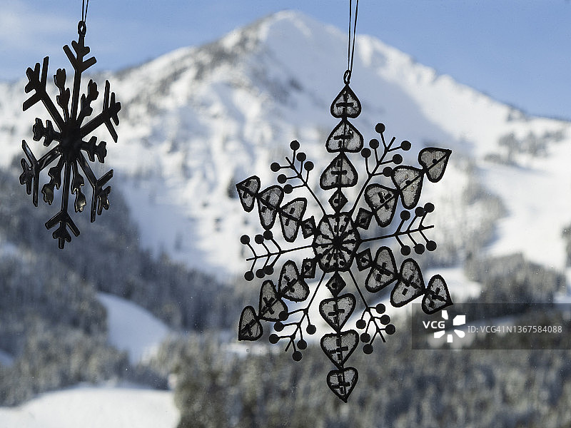 窗户上悬挂的雪花装饰品与雪山背景图片素材