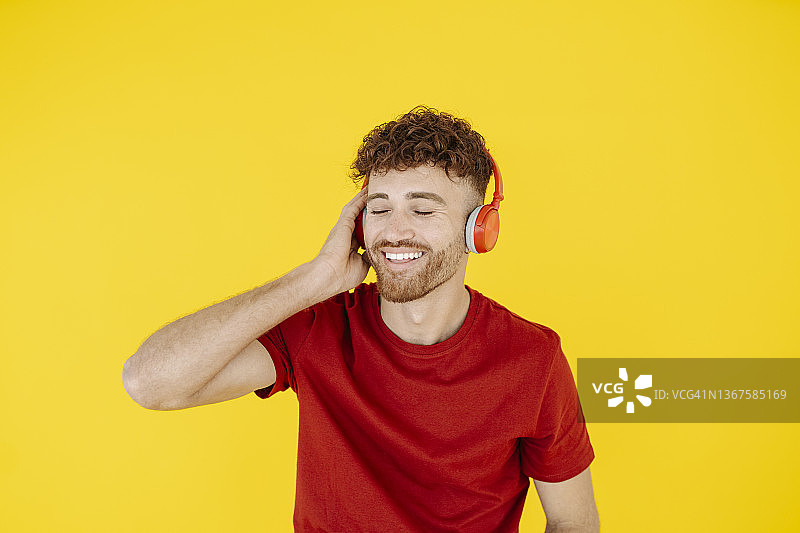 戴着红色耳机听音乐的年轻男人肖像图片素材
