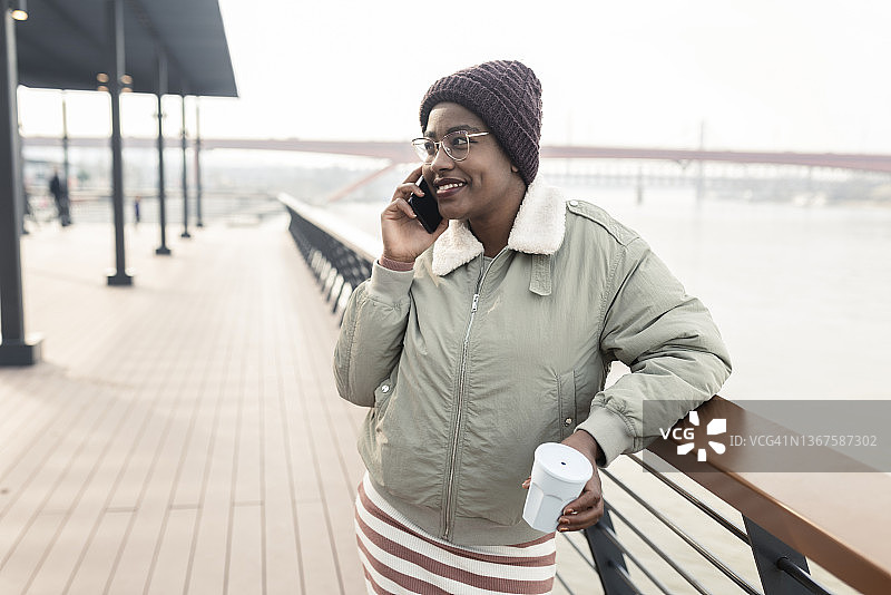 美丽的蓬松发型女孩坐着喝咖啡和打电话图片素材