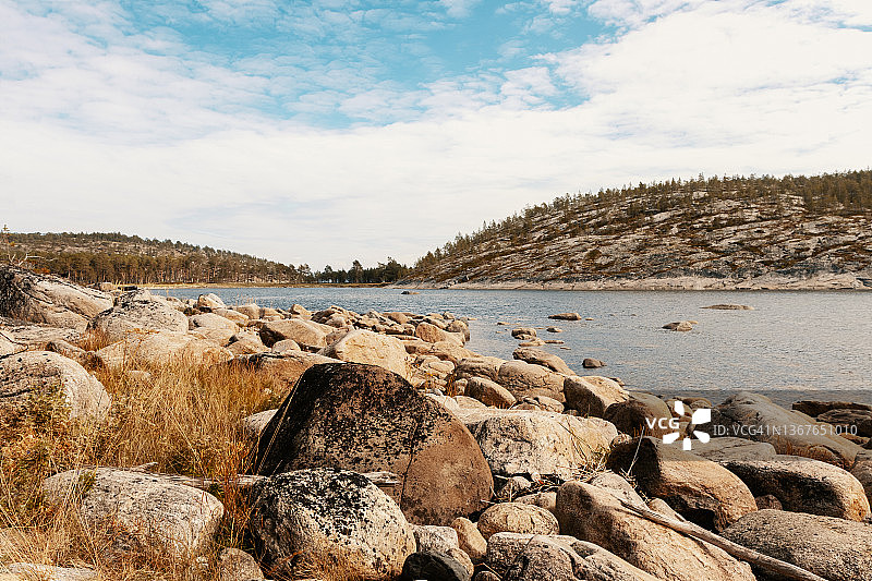 湖中的浅水湾，岸边有巨石。卡累利阿的秋季风光。稀疏沙漠地区多石的海边，北欧的极地气候图片素材