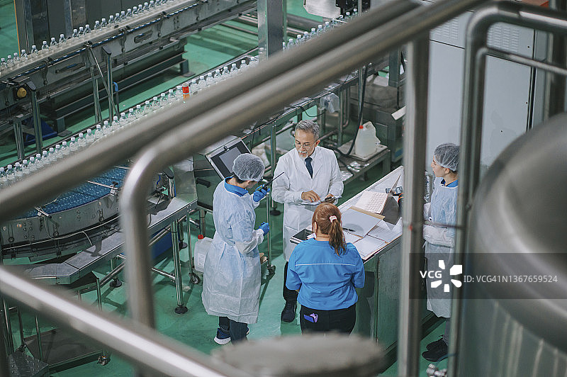 中国工厂检查员与生产线工人讨论矿泉水质量图片素材