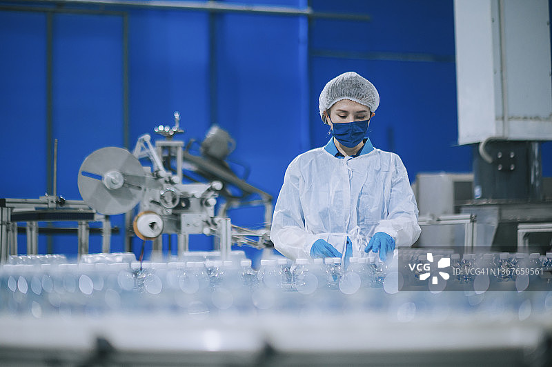亚裔女工在饮用水厂生产线上检查水瓶图片素材