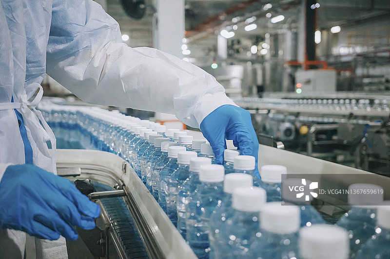 亚裔女工在饮用水工厂生产线上检查水瓶特写图片素材
