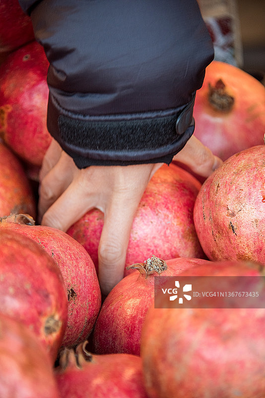 从石榴堆中取出一个石榴图片素材