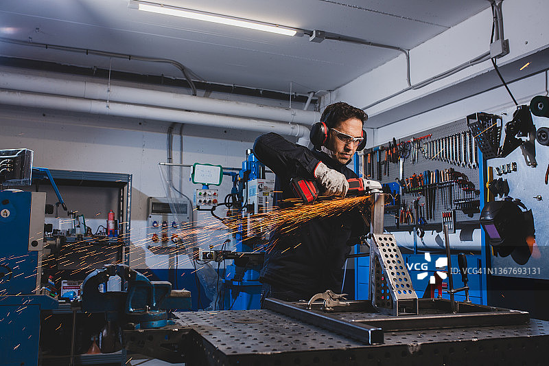 在车间使用角磨机并穿着防护服的男人图片素材