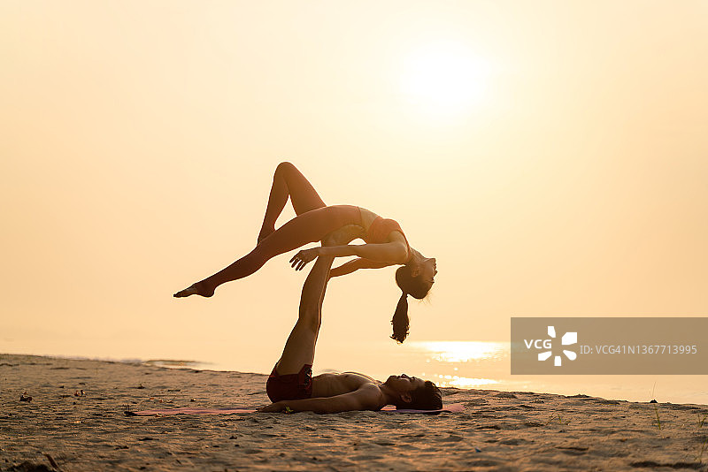 年轻夫妇在海滩上练习瑜伽图片素材