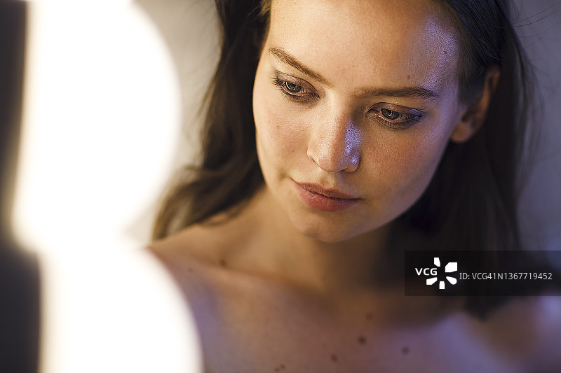 在镜子前，一位拥有雀斑和痣的漂亮女人。图片素材