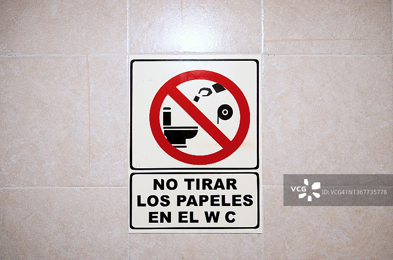 公共浴室瓷砖墙上的西班牙语“请勿在马桶内扔纸”提示图片素材