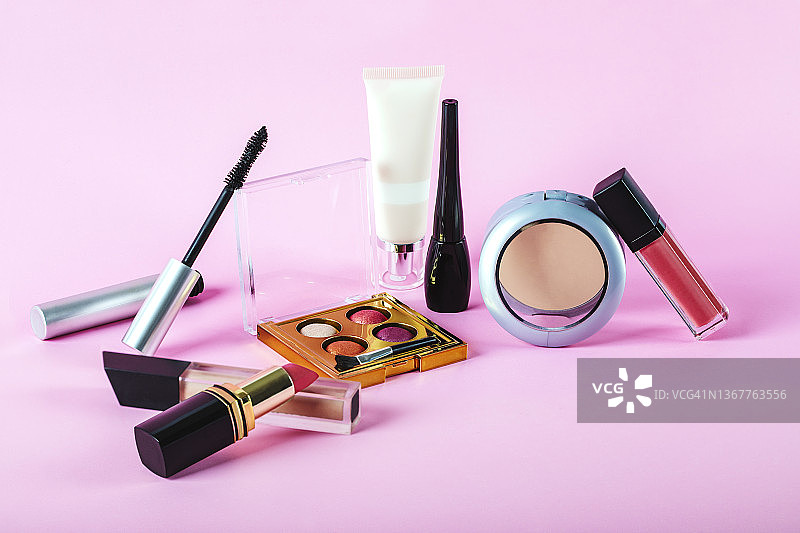 粉色背景上的各种美容产品和专业彩妆化妆品图片素材