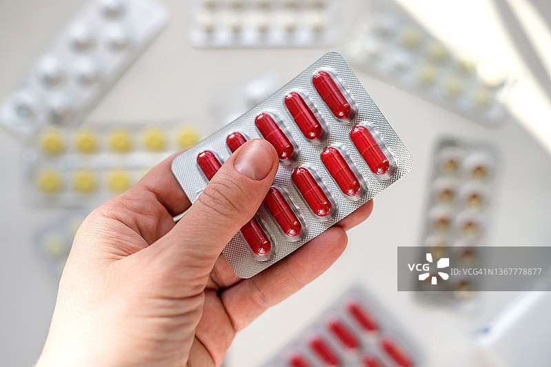 女人手拿红色药丸特写图片素材
