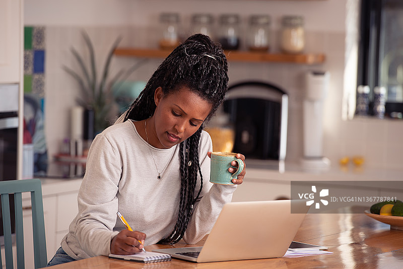 女人一边使用笔记本电脑一边记笔记图片素材