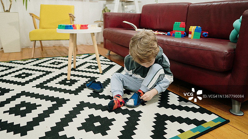 小孩坐在地板上穿鞋图片素材