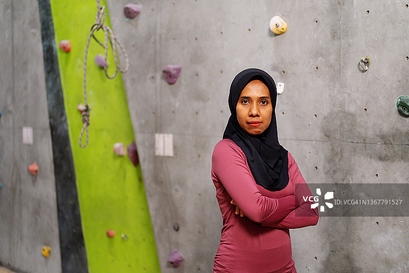 自信的穆斯林女攀岩运动员在健身房攀岩墙前图片素材