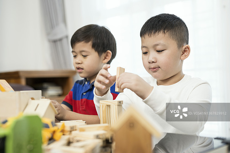 自主学习提升情商：学童在客厅的桌子上一起玩木制玩具积木的侧视图图片素材