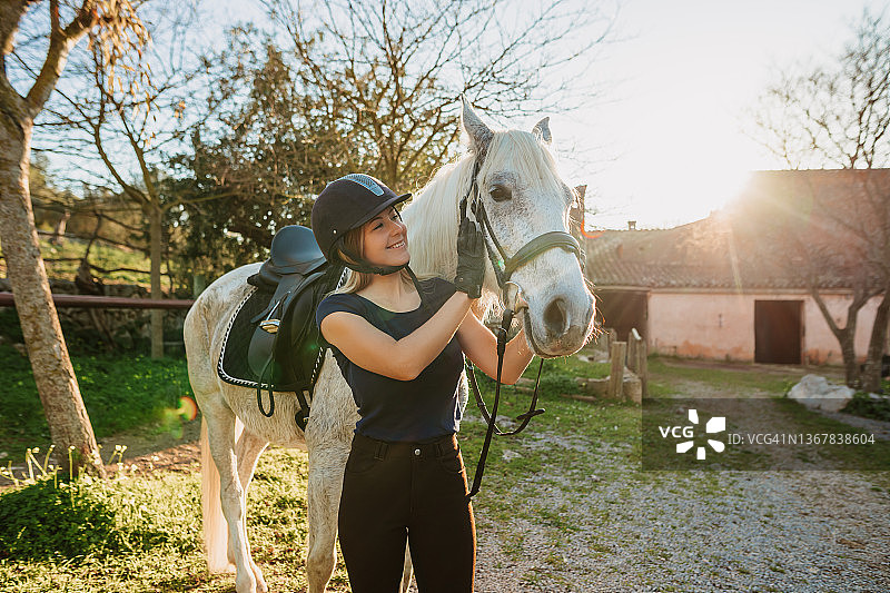在马略卡岛乡村马厩户外骑行训练后拥抱马匹的金发女人图片素材