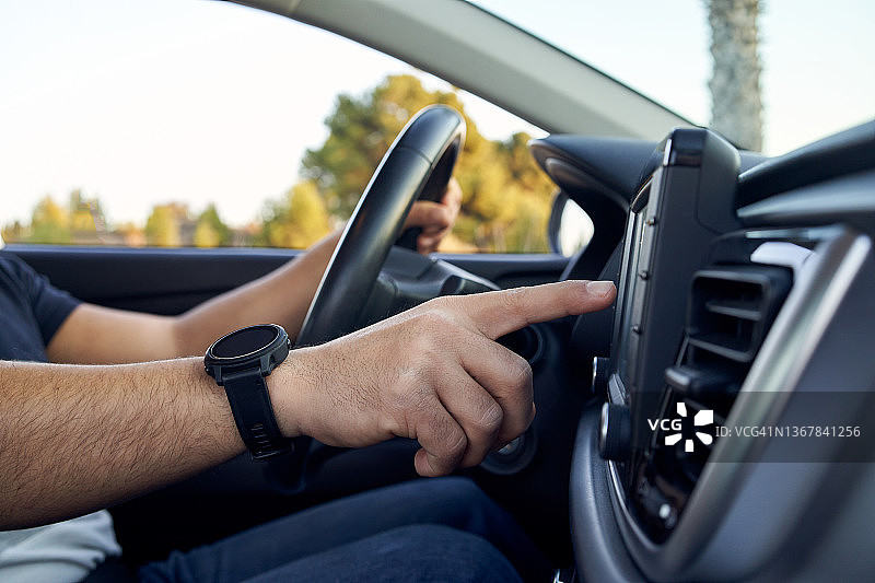 车内拍摄的年轻男子触摸车载导航屏幕的侧面特写图片素材