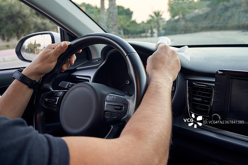 男子用纸巾清洁汽车内饰特写图片素材