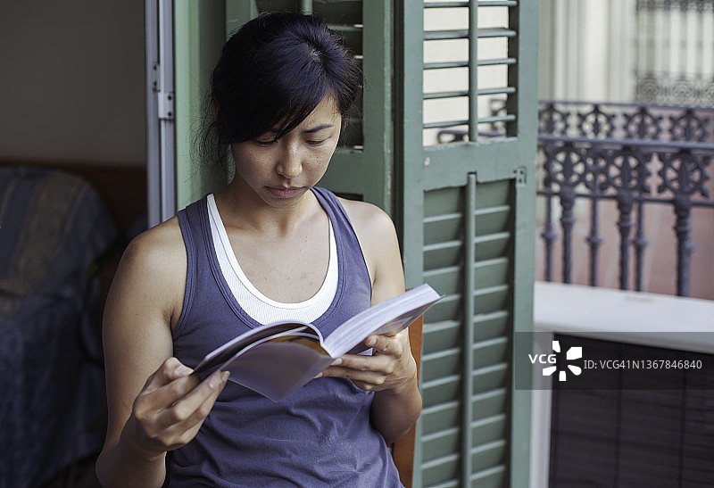 坐在阳台上看书的年轻亚洲成年女性图片素材