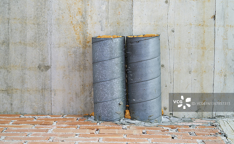 白天，混凝土墙上损坏的供暖管道。废弃建筑物，供暖管道已断开。图片素材